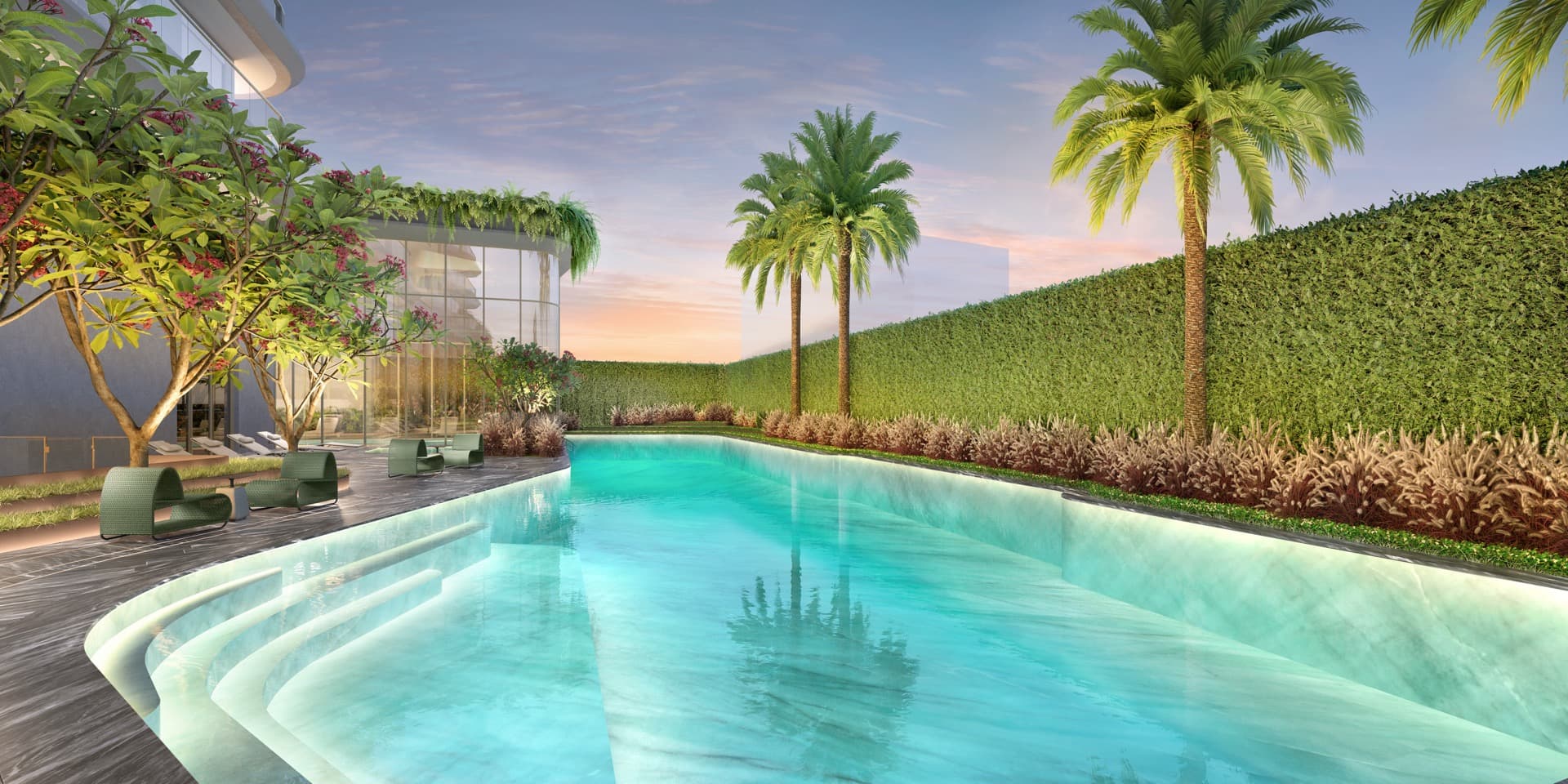 Piscina descoberta ao entardecer, com as palmeiras refletidas na água e um muro verde alto fechando o jardim
