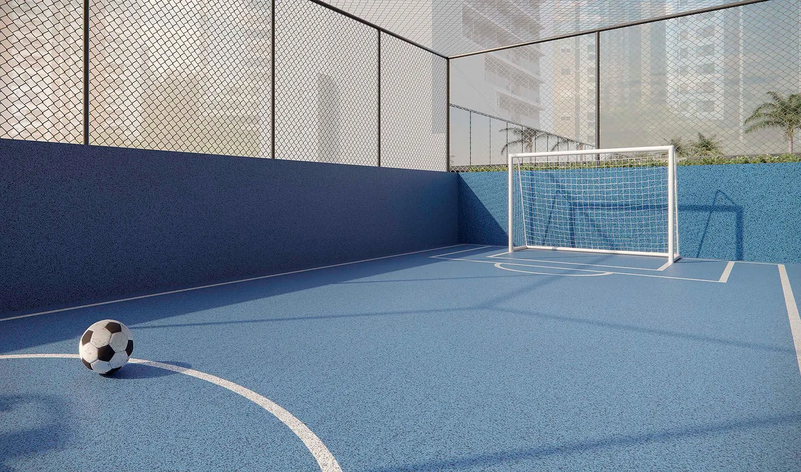 A quadra de chute a gol, de piso azul, com o gol e uma bola, cercada por tela.