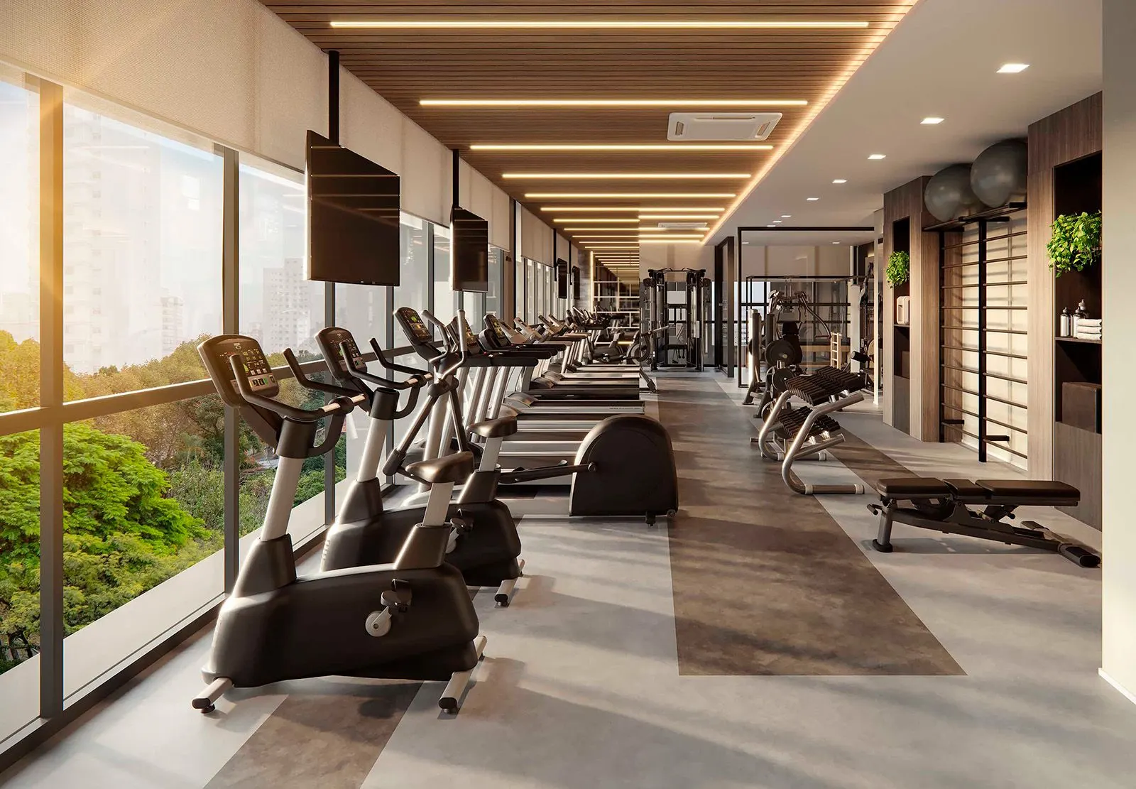 O fitness: esteiras e bicicletas enfileiradas junto de uma parede de vidro aberta para a mata, sob um forro de ripas de madeira.