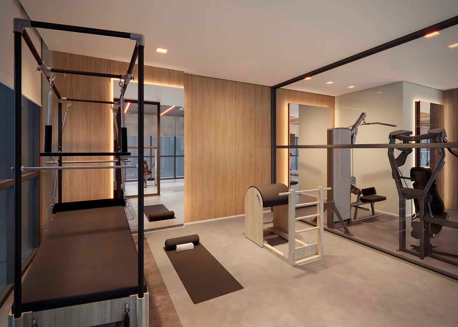 A sala de pilates, com aparelhos de madeira e metal sobre o piso cinza e um painel de madeira iluminado.