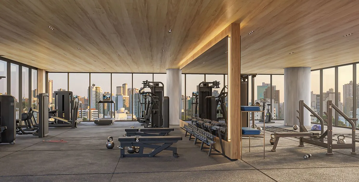 O fitness envidraçado com aparelhos de musculação e a cidade ao fundo.