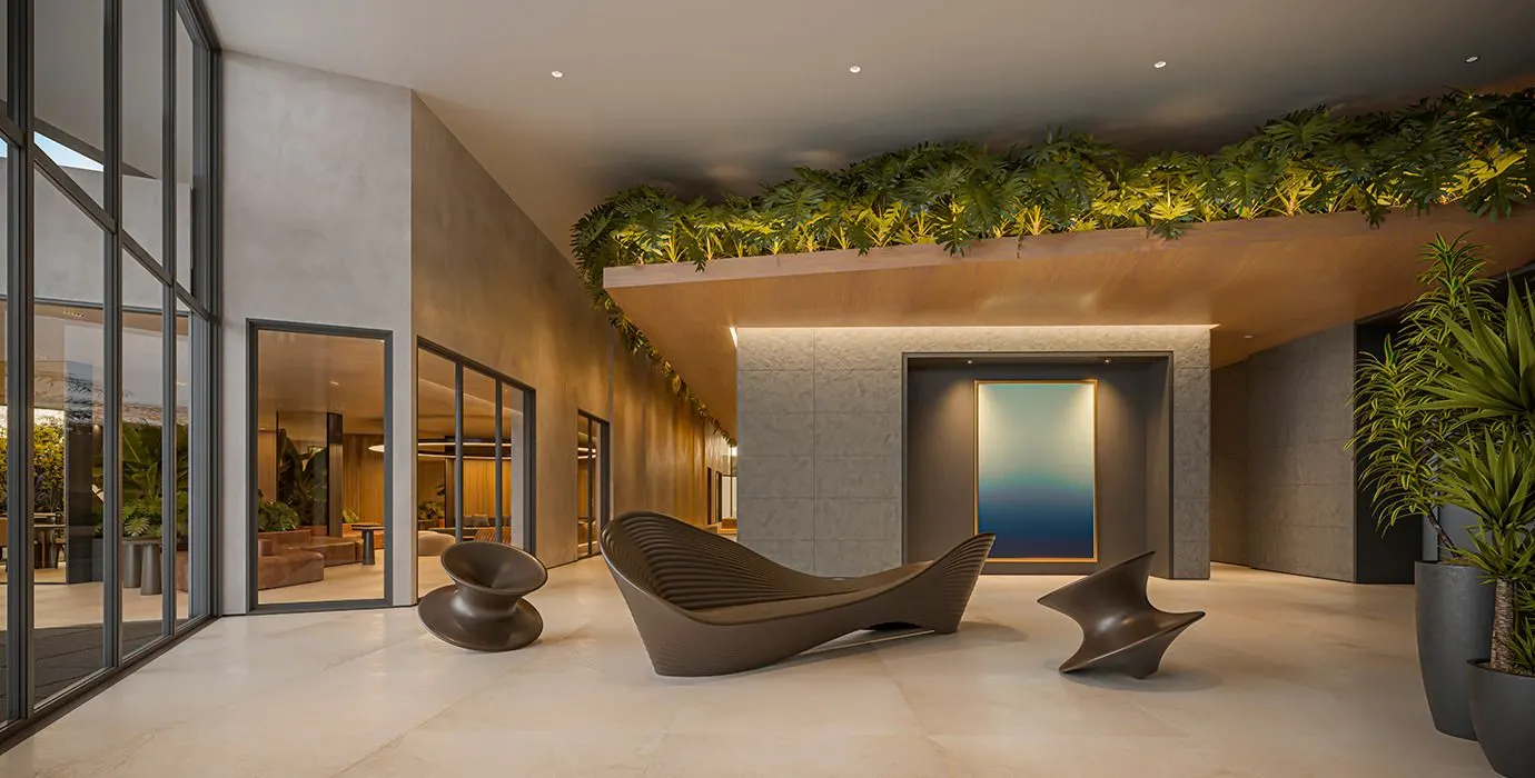 O lobby de pé-direito alto, com folhagens pendendo do teto de madeira, poltronas esculturais e um painel azul ao fundo.