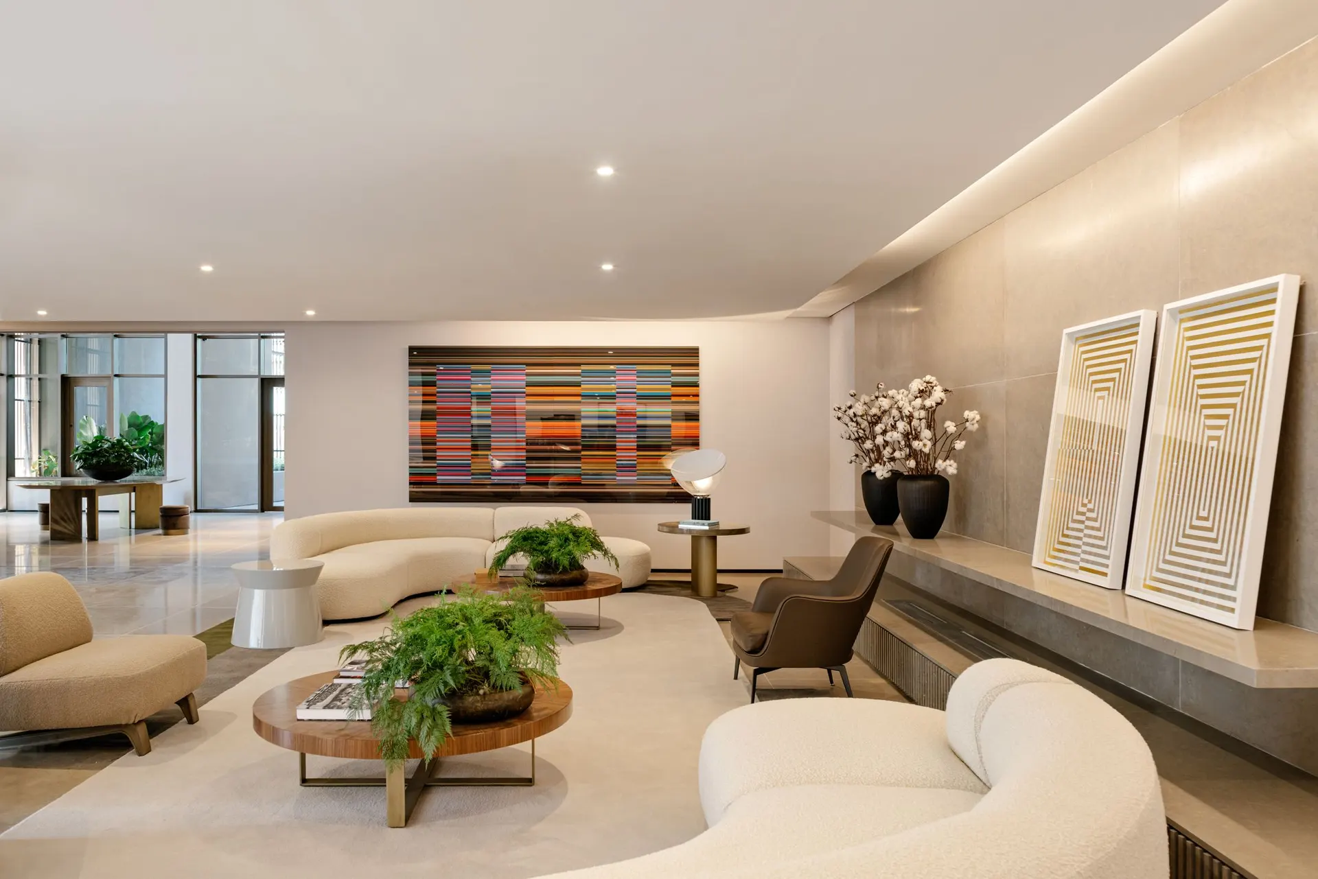 O lounge do térreo, com sofás curvos, mesa de madeira e duas obras de arte na parede.