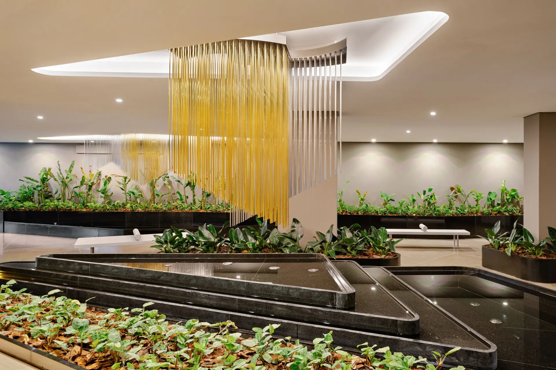 O salão de festas, com o lustre dourado em fios suspensos sobre o jardim interno.