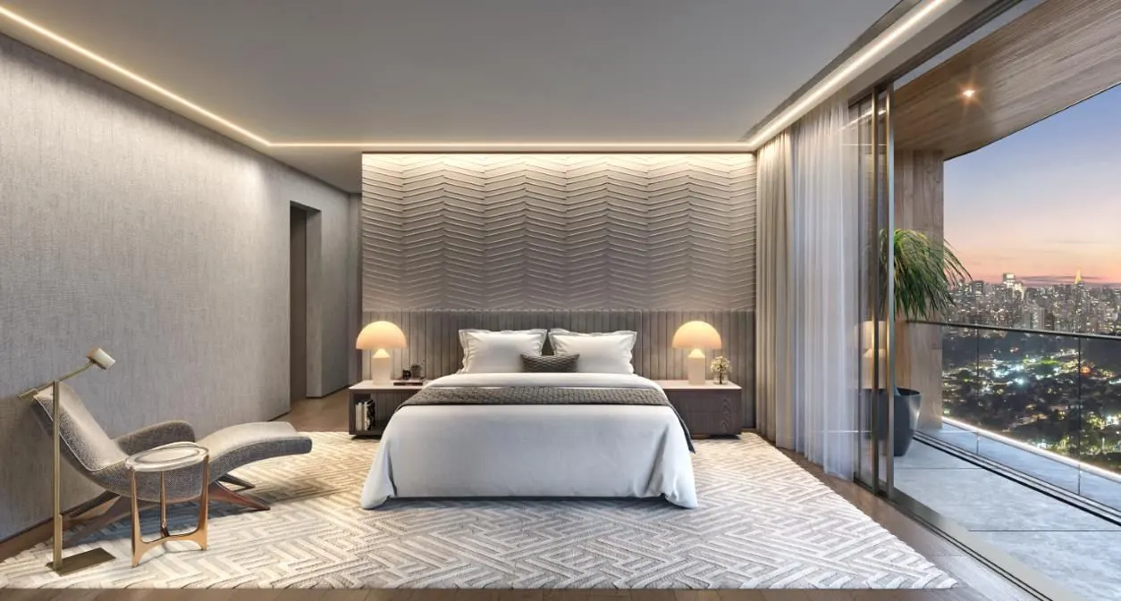 Uma suíte decorada, com cama de casal, poltrona e a janela de piso a teto para a cidade.