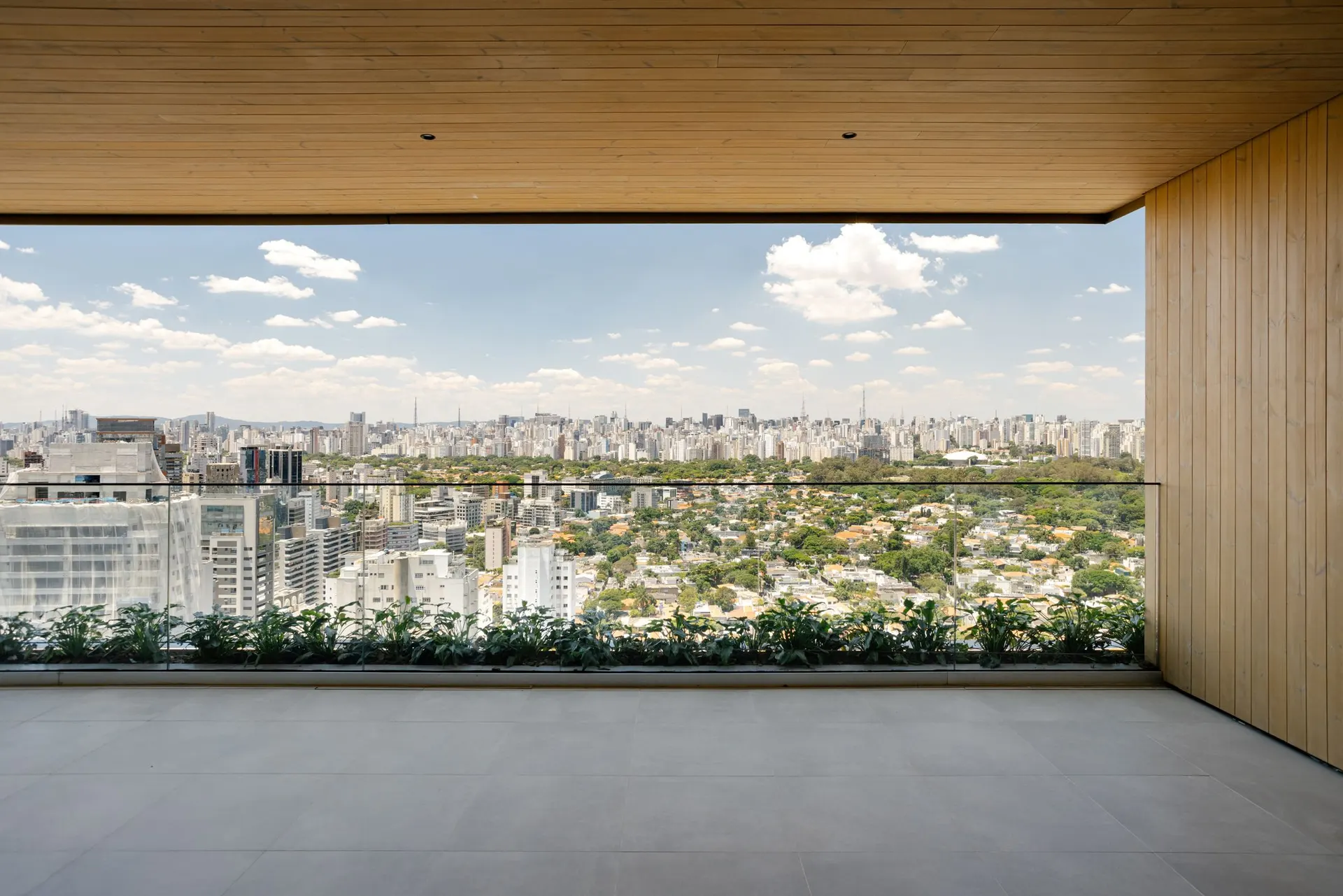 O terraço da cobertura, com forro de madeira e floreira, aberto para a Vila Nova Conceição e o skyline de São Paulo.