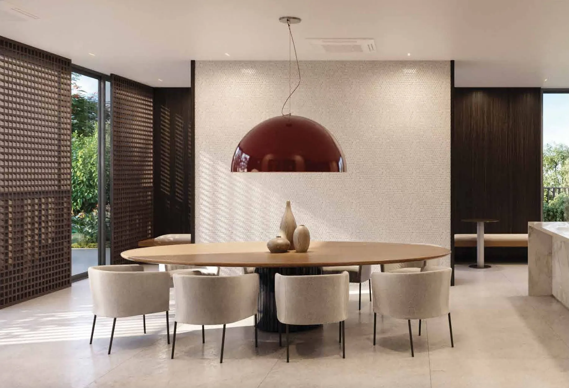 O espaço gourmet: mesa redonda sob um pendente vermelho, cozinha aberta e treliça de madeira.