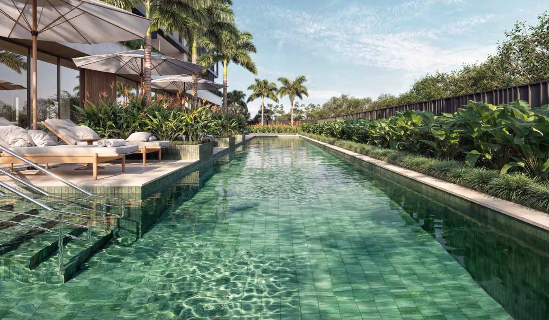 A piscina descoberta de raia longa, com espreguiçadeiras e jardim tropical nas bordas.