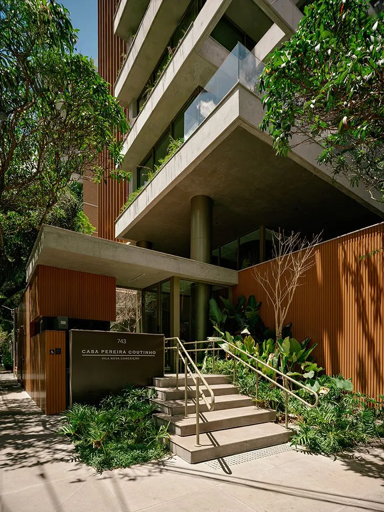 A escada da entrada sob a marquise de concreto, com o jardim dos lados.