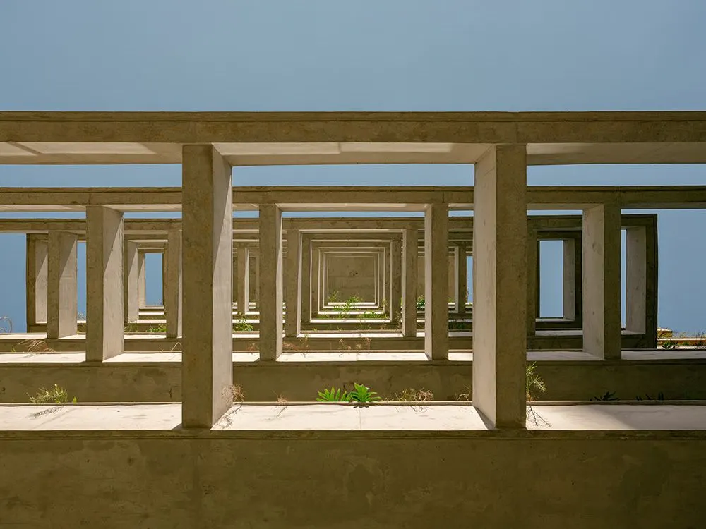 Uma varanda vista de lado: os quadros de concreto um atrás do outro, como molduras em sequência, com o céu azul ao fundo.