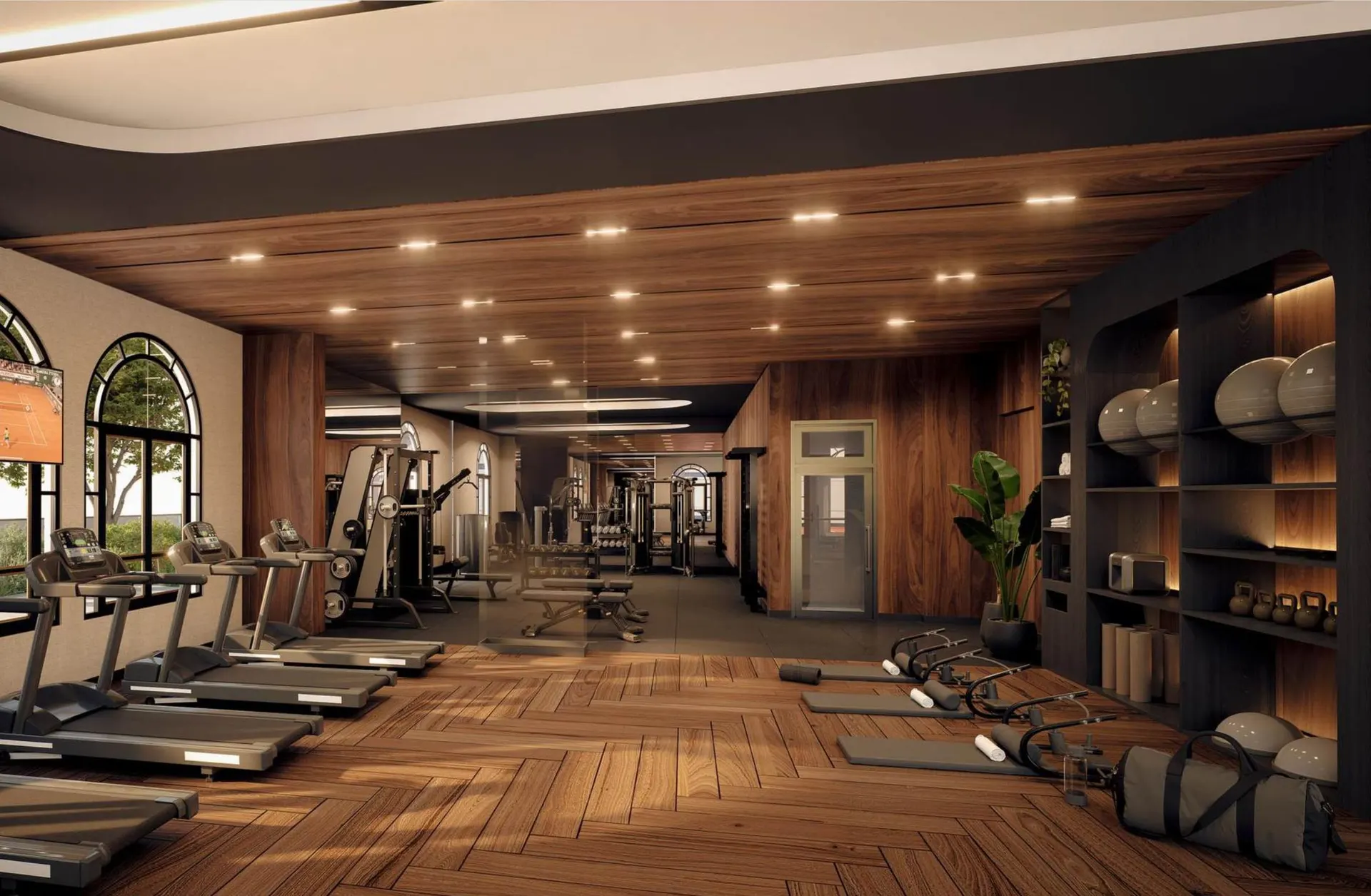 O fitness center, com esteiras diante de janelas em arco e piso de madeira.