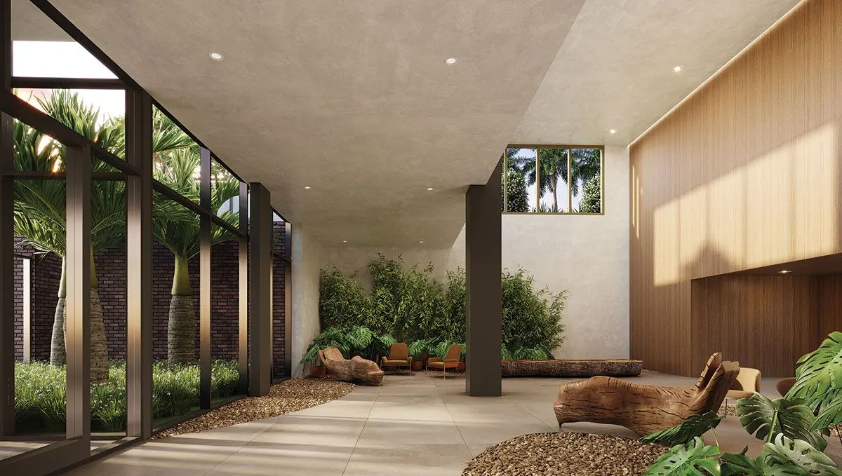 O lobby de pé-direito alto com paredes de madeira, um banco de tronco e um jardim interno de folhagens.