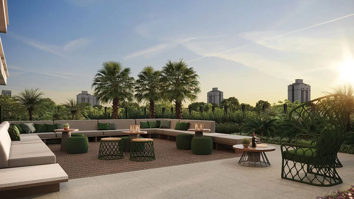 O lounge externo ao pôr do sol, com sofás e mesas baixas entre palmeiras.