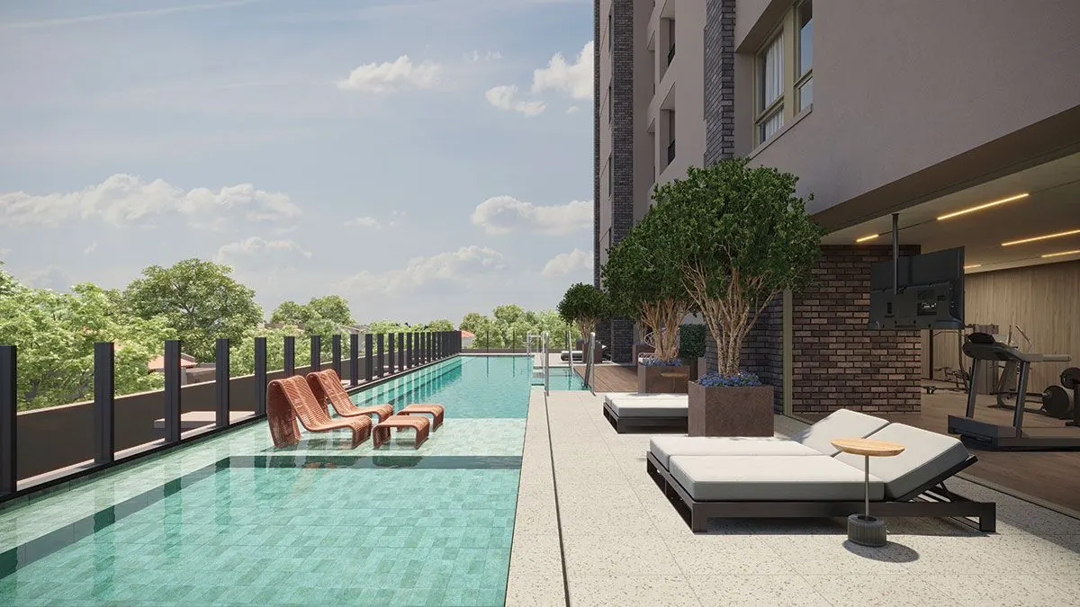 A piscina descoberta e comprida ao longo do guarda-corpo, com espreguiçadeiras e a cidade ao fundo.