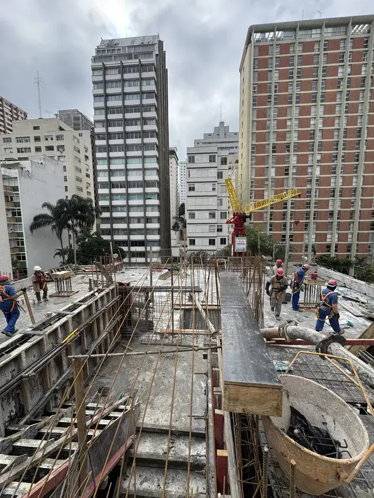O canteiro visto do alto: as fôrmas e as armaduras da laje, um caminhão-betoneira na rua e os prédios vizinhos em volta.