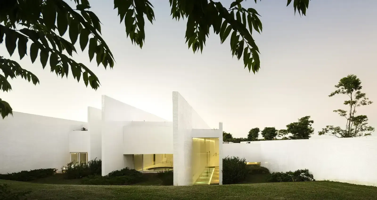 O spa: volumes brancos entre o gramado e as árvores.