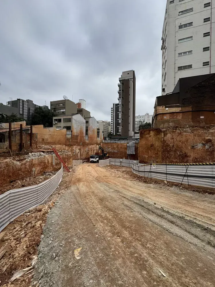 O fundo de terra batida entre os muros de contenção, com os prédios da vizinhança em volta.