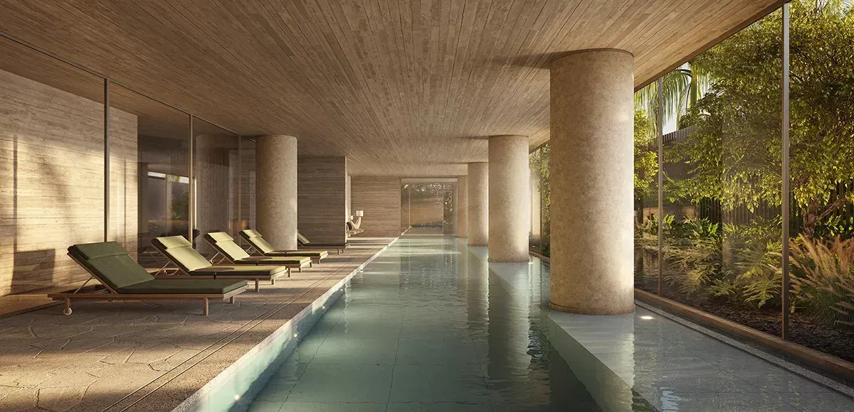 A piscina coberta: a raia longa entre pilares de concreto, espreguiçadeiras de um lado e o jardim atrás do vidro do outro.