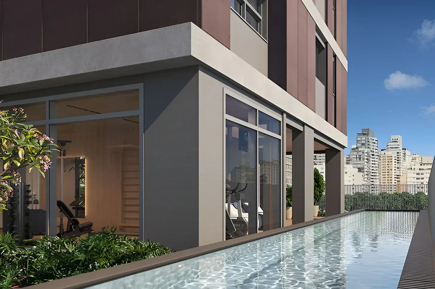 A piscina do residencial junto à torre: a água comprida ao longo do vidro do salão, as jardineiras na borda e o céu azul.
