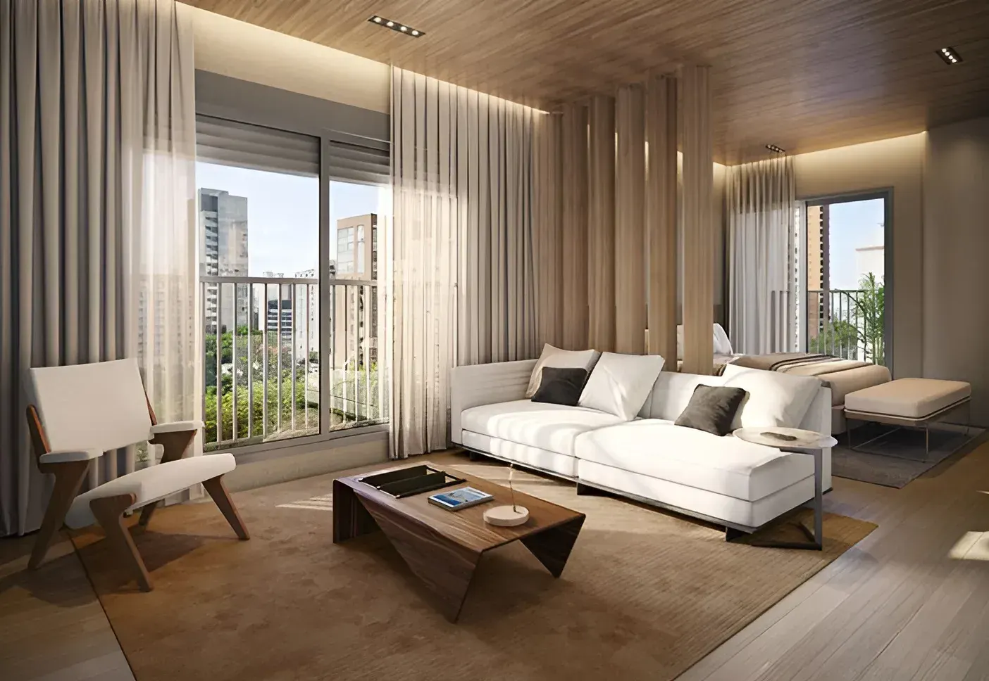 Um studio: o sofá branco e a poltrona de madeira sobre o tapete, a mesa de centro e a janela com cortinas leves e as árvores da rua.