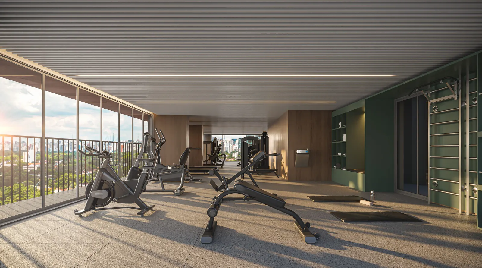 As bicicletas e os aparelhos da academia junto ao guarda-corpo de vidro, com o skyline ao fundo.